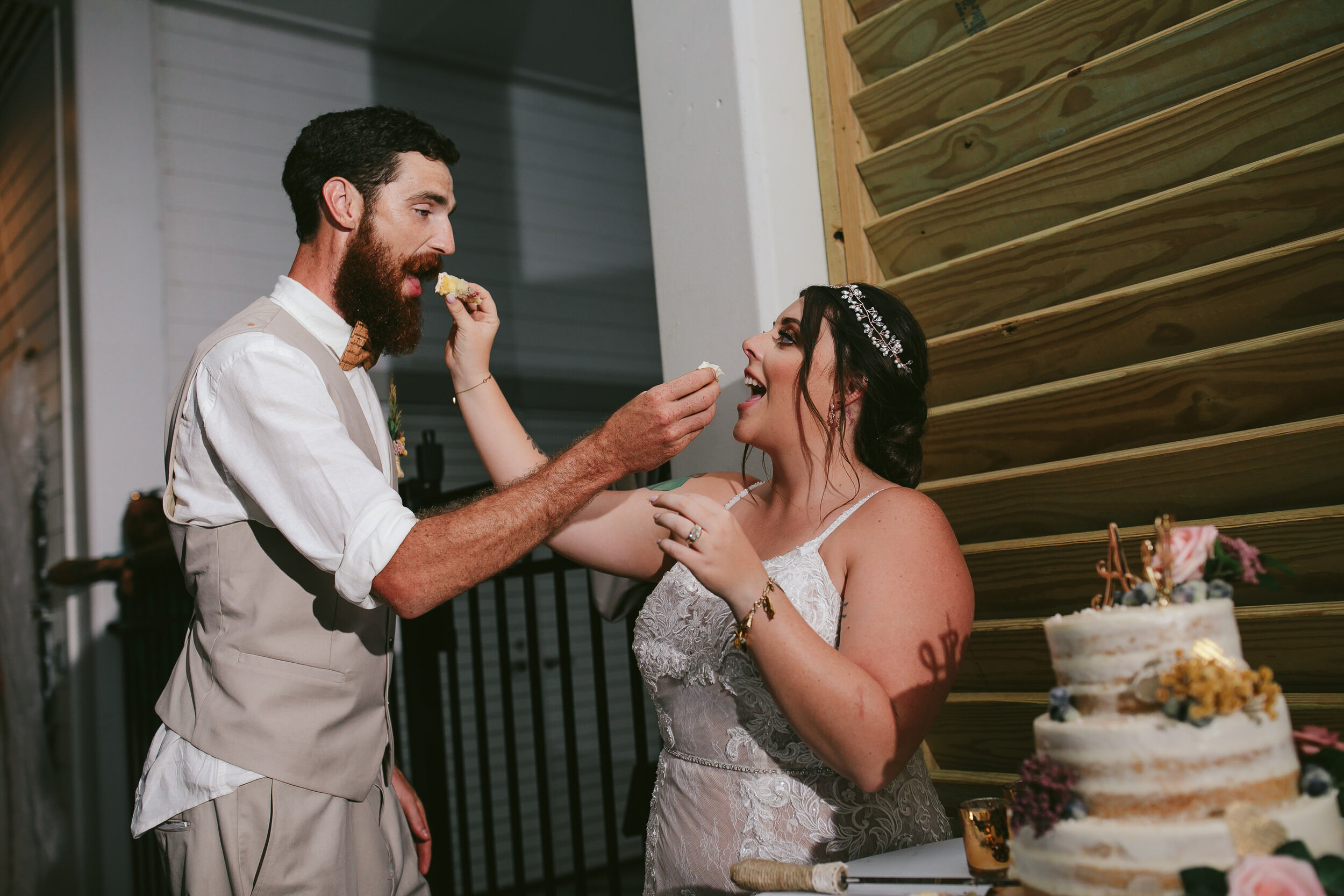 Bride-and-Groom-Feeding-Each-Other-Cake-Port-St-Joe-Backyard-Wedding-Reception