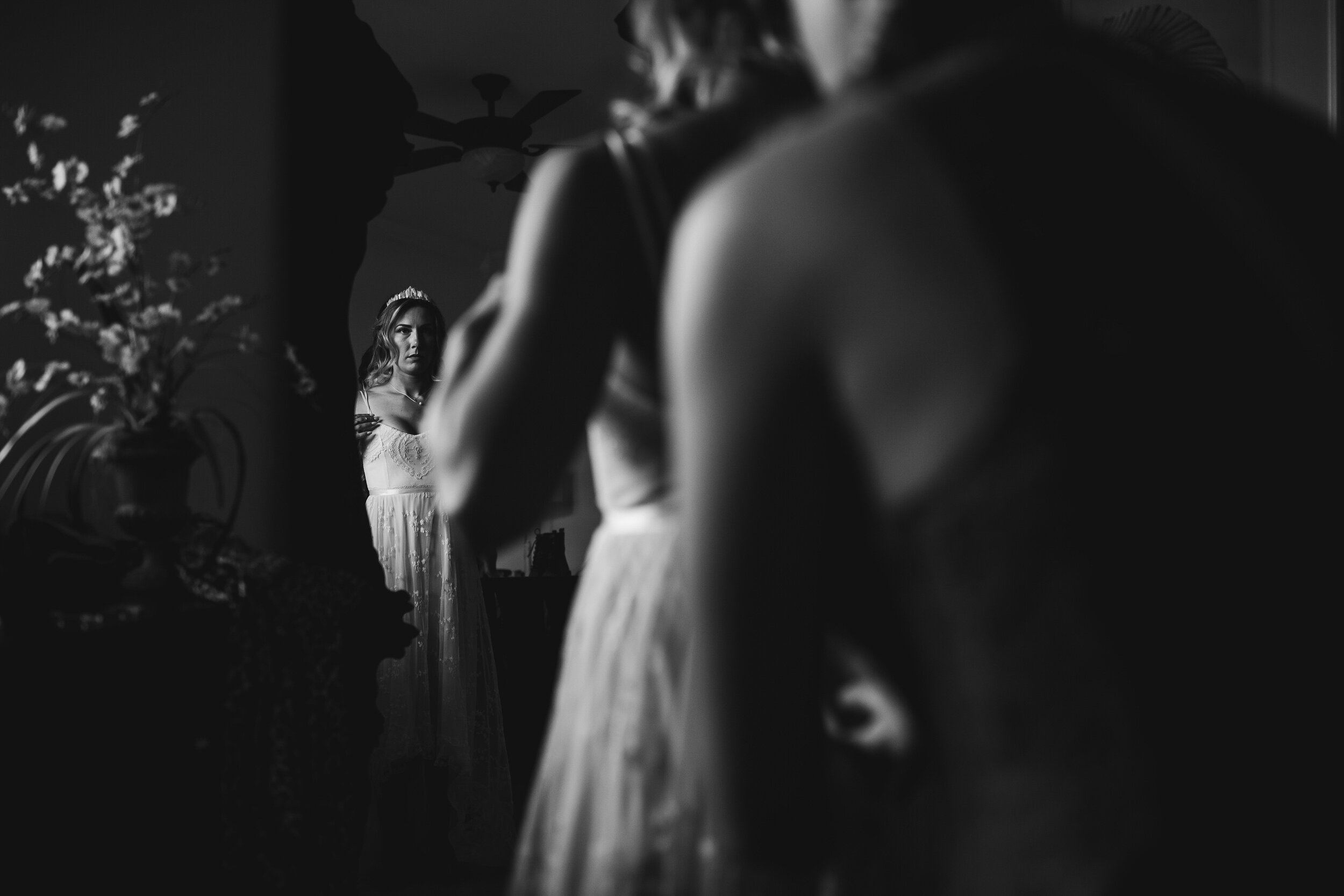 Bride looking in mirror getting into her dress