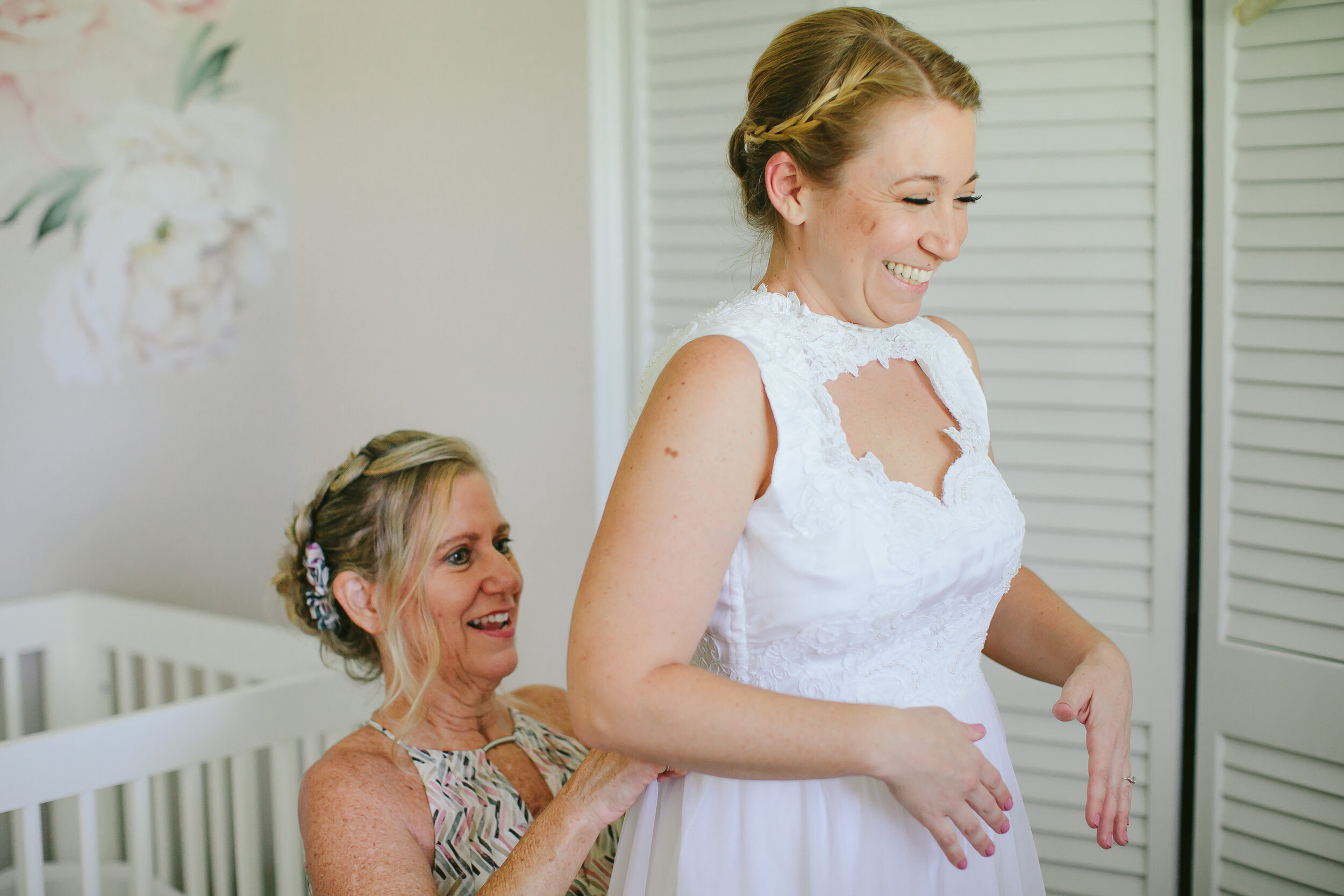 Mom Helping Bride into her dress laughing on wedding day