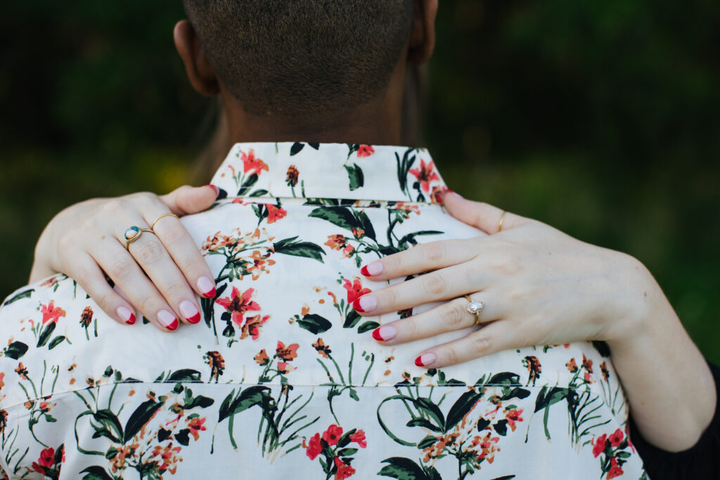 Engaged Couple Embracing painted nails on Floral top. 