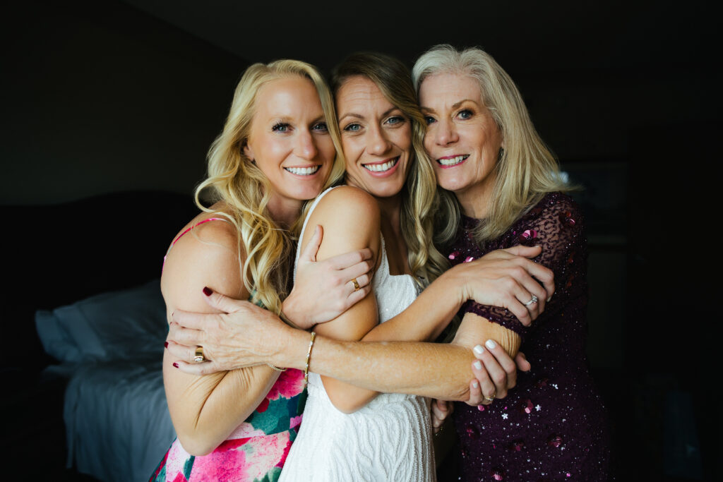 Bride, her sister and her mother pose for a portrait on her Wedding Day.
