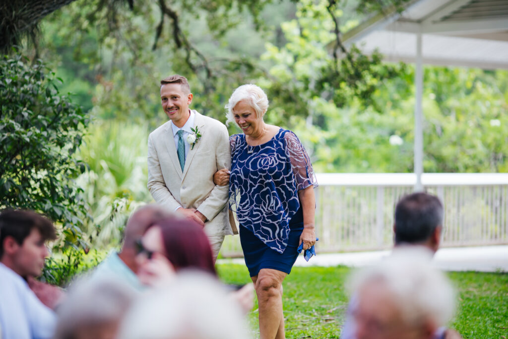 Groom walks up the aisle with his mother for his Garden Wedding Ceremony