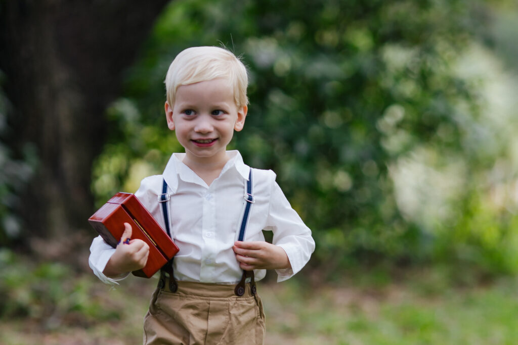 Cute Ring Bearer smiling as he walks up the aisle to the Garden Wedding Ceremony