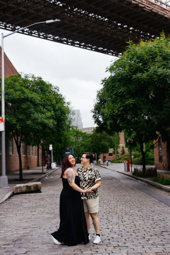 Queer Couple dancing on the cobblestone streets in Dumbo Brooklyn during their photo session with Tiny House Photo