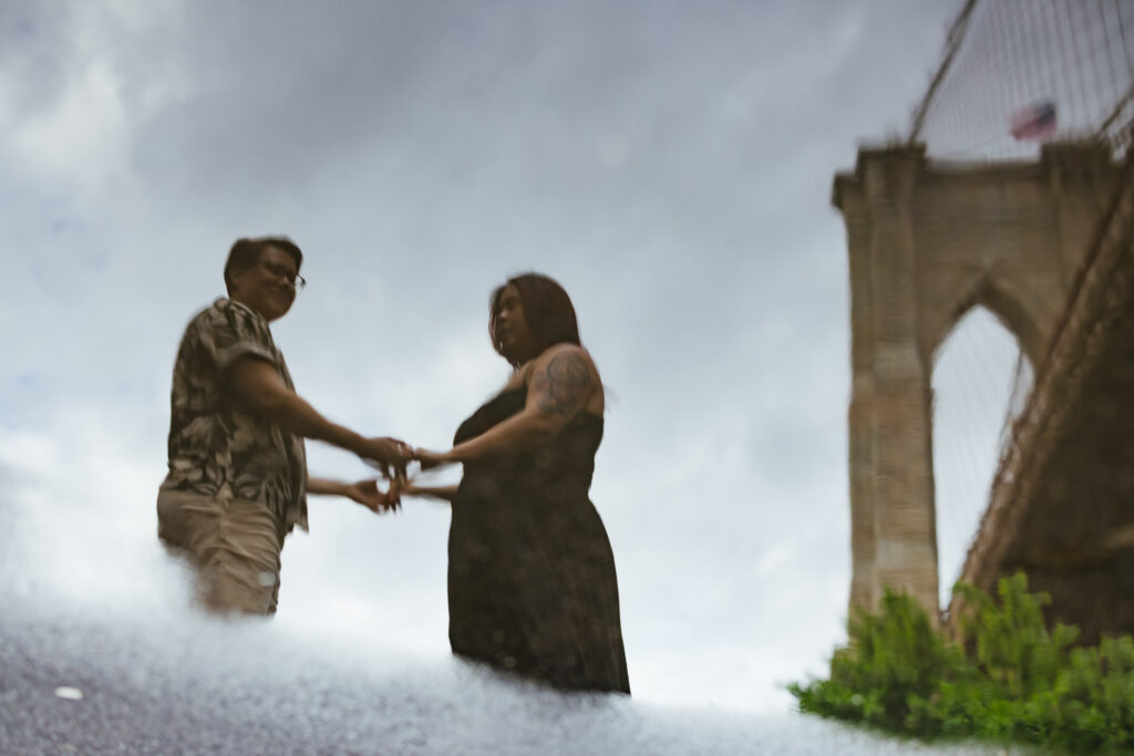 Queer Couple Reflection in Puddle Brooklyn Bridge